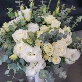 White rose and lisianthus arrangement with eucalyptus in a clear glass vase