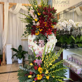 Tall floral arrangement with red lilies, white orchids, and yellow blooms