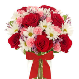 Bouquet of red roses, white daisies, and pink carnations in a clear vase with red bow