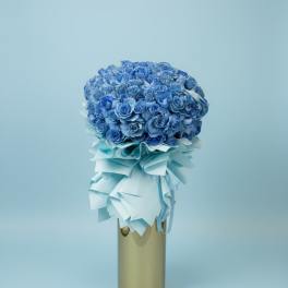 Blue rose bouquet with a pale ribbon wrap in a gold vase