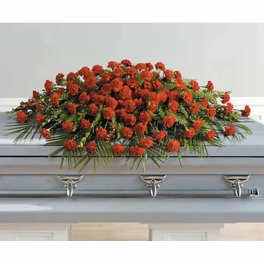 Red floral casket spray with greenery on a gray casket