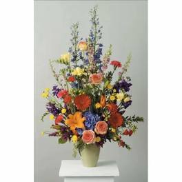 Tall mixed bouquet in a pale green vase with multicolored blooms