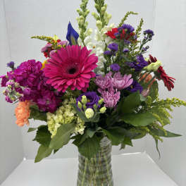 Colorful mixed bouquet in a clear glass vase with gerbera daisies and snapdragons