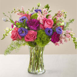 Mixed pink and purple flowers arranged in a clear glass vase