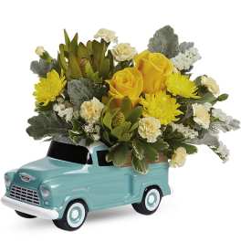 Yellow roses and chrysanthemums arranged in a turquoise truck planter