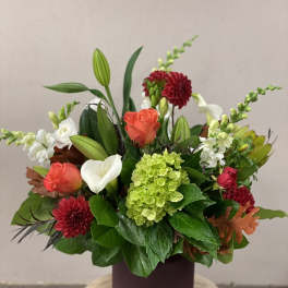 Mixed floral arrangement in a dark vase with roses, calla lily, and hydrangea