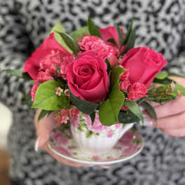 Pink rose and carnation arrangement in a floral teacup and saucer