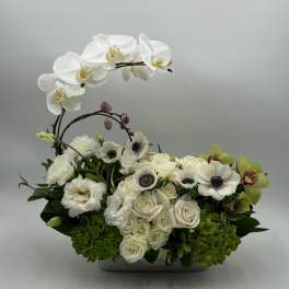 White orchids and roses arranged in a low rectangular container