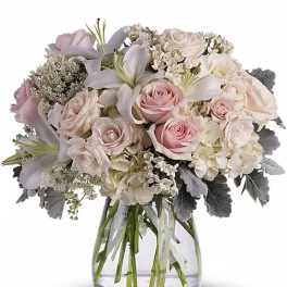 Blush and white bouquet of roses and lilies in a clear glass vase