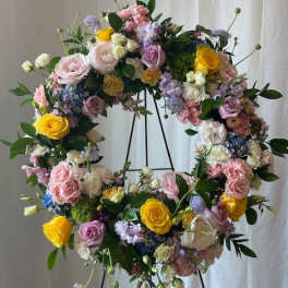 Large floral wreath on a black stand with pastel roses and mixed blooms