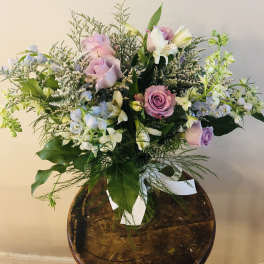Bouquet of pink and lavender roses with white flowers in a glass vase