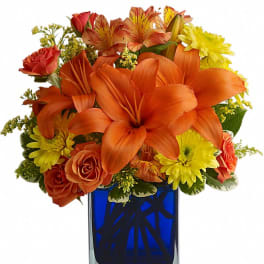 Orange and yellow flower arrangement in a blue glass vase