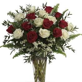 Red and white roses arranged in a clear glass vase.