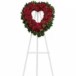 Heart-shaped red rose wreath on a white easel