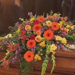 Large colorful floral spray on a wooden casket
