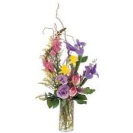 Mixed bouquet of purple, pink, and yellow flowers in a glass vase