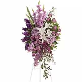 Tall purple floral standing spray on an easel with white lilies