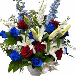 Red, white, and blue bouquet with roses and lilies in a vase