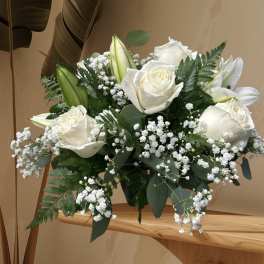 White roses and lilies arranged with baby's breath in a vase