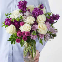 Bouquet of white roses and purple flowers in a glass vase