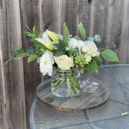 White flowers and pale yellow lilies in a clear glass vase
