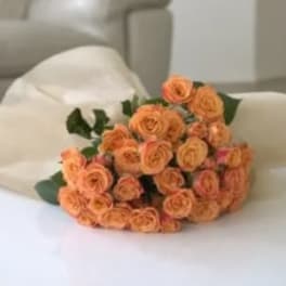 Bouquet of peach spray roses wrapped in white paper