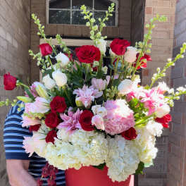 Large red hatbox arrangement with roses, hydrangeas, and lilies