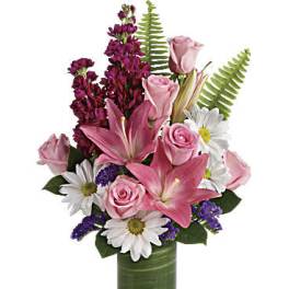 Pink lilies and roses with white daisies in a glass vase