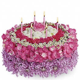 Round pink floral cake with lit candles