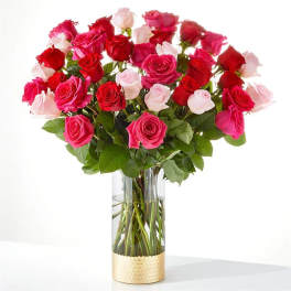 Bouquet of red, pink, and white roses in a clear glass vase