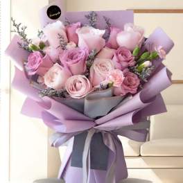 Bouquet of pink and lavender roses wrapped in purple paper