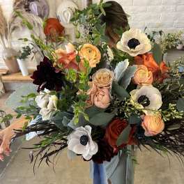Large bouquet of peach, orange, and white flowers with dark accents