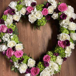 Heart-shaped floral arrangement with pink, white, and purple roses