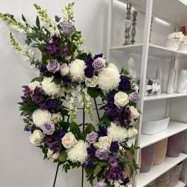 Purple and white floral wreath on a metal stand