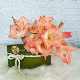 Peach gladiolus arrangement in a green box with a thank-you tag