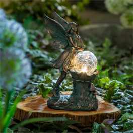 Fairy figurine holding a glowing glass orb on a wood slice