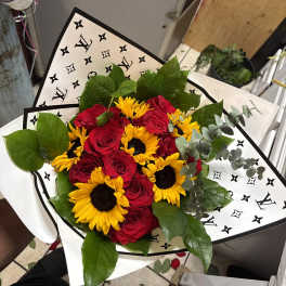 Bouquet of red roses and yellow sunflowers wrapped in patterned paper