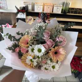Bouquet of pink roses, gerbera daisies, and white daisies wrapped in white paper