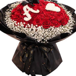 Red rose bouquet with white floral lettering and a black ribbon wrap