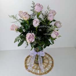 Bouquet of pale lavender roses in a glass vase with a ribbon