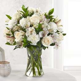 White roses and carnations arranged in a clear glass vase