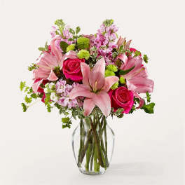 Pink lilies and roses arranged in a clear glass vase