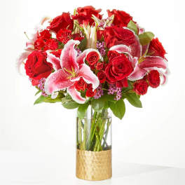 Red roses and pink lilies arranged in a glass vase