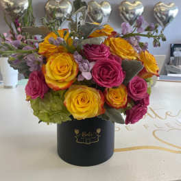 Yellow and pink roses arranged in a black hat box