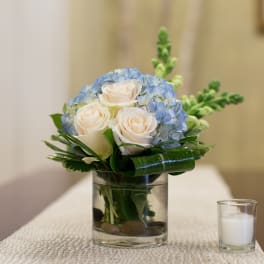 White roses and blue hydrangeas in a glass vase