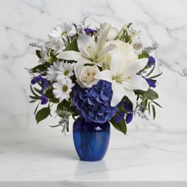 White lilies, daisies, and blue hydrangea in a cobalt vase