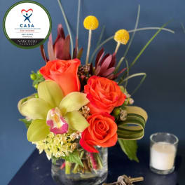 Orange roses and a pale green orchid in a glass vase