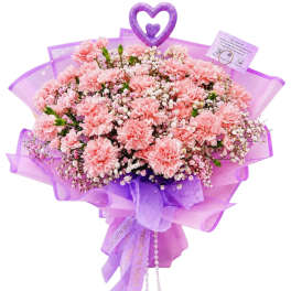 Pink carnation bouquet wrapped in purple paper with a heart topper