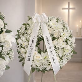 White funeral wreath on a stand with a memorial ribbon