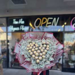 Bouquet of Ferrero Rocher chocolates and folded dollar bills in pink wrap